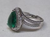 une image d'une bague avec une pierre verte entourée de diamants