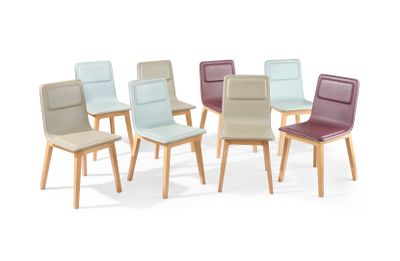 Plusieurs chaises de différentes couleurs sont disposées en cercle sur une surface blanche.