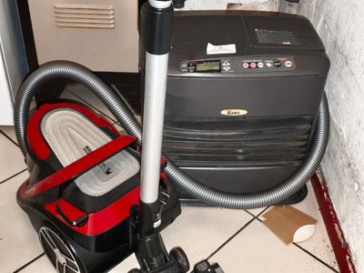 un aspirateur posé par terre à côté d'une valise