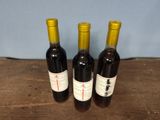 three bottles of wine sitting on top of a wooden table