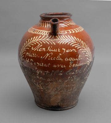 un vase marron portant une inscription, posé sur une table