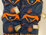 Deux t-shirts ornés de logos orange et bleus sont posés sur une table blanche