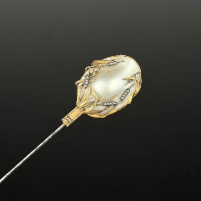 a close up of a gold and pearl broocher on a stick