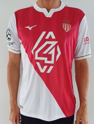 Le jeune homme porte un maillot de foot rouge et blanc.