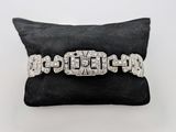 un bracelet en or blanc et diamants posé sur un coussin noir