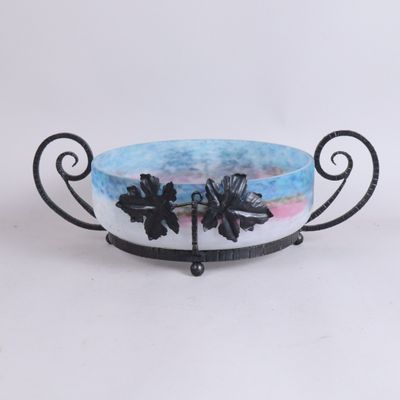 un bol bleu orné de fleurs noires, posé sur un socle