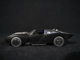 a black toy car that is sitting on a black surface