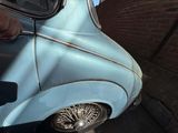 a blue car that is parked next to a brick wall