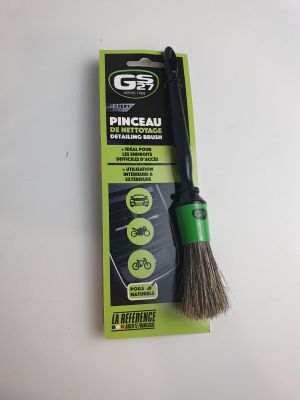 un gros plan d'une brosse de nettoyage verte et noire posée sur une surface blanche