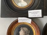 three framed portraits of women and a man are on a table