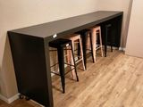 une longue table avec quatre tabourets dans un coin de la pièce