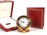 a small gold clock in a red box with a white face