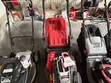 Plusieurs tondeuses à gazon sont alignées dans un garage