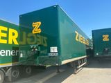 two green semi trucks parked next to each other in a parking lot