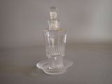 a clear glass bottle with a glass stopper sitting on a plate