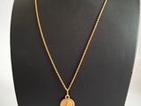 un collier en or avec une pièce de monnaie sur le cou d'un mannequin