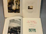 two open books on a table with a picture of a landscape in the background