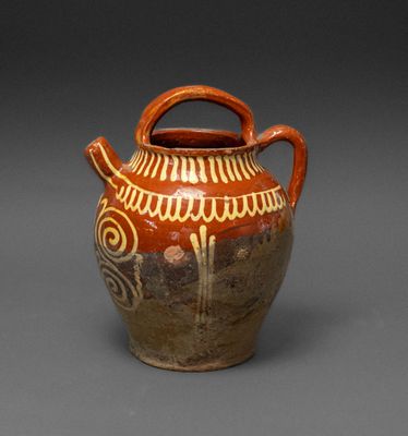 a brown and white vase with handles on a gray surface