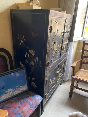 a cabinet and a chair in a room next to a window