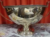 a silver bowl on a marble table with a red curtain behind it