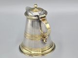 a silver and gold bell with a rope around it on a white surface