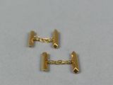 a close up of two gold cufflinks on a white surface