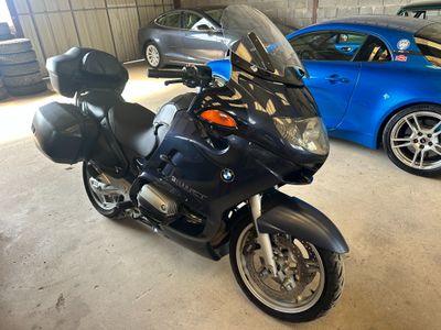 une moto noire garée dans un garage à côté d'une voiture bleue