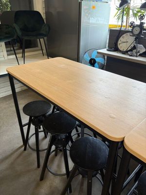 tables and stools in a room with a window and a painting on the wall