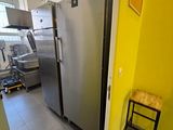un réfrigérateur en acier inoxydable dans une cuisine aux murs jaunes
