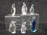 three clear glass figurines of birds on a black background