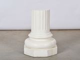 un pilier blanc avec un socle blanc posé sur un sol en ciment