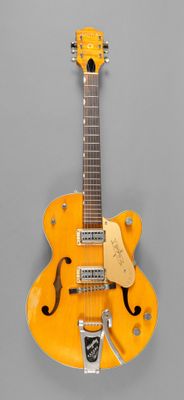 une vieille guitare électrique jaune posée sur une surface grise