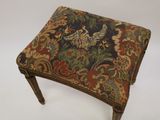 an antique foot stool with a bird design on the seat