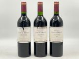 trois bouteilles de vin rouge posées l'une à côté de l'autre sur une surface blanche