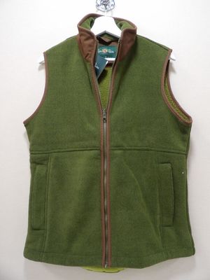 Le gilet est vert, avec des bordures marron et une fermeture éclair sur le devant.