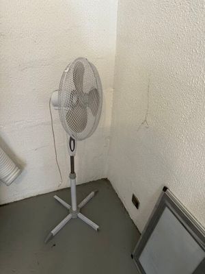un petit ventilateur dans un coin de la pièce, à côté d'un téléviseur