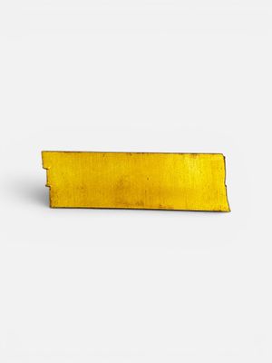 a close up of a yellow piece of metal on a white surface