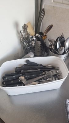 un saladier posé sur un plan de travail de cuisine, contenant des ustensiles