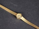 une image représentant une montre-bracelet en or posée sur une surface noire