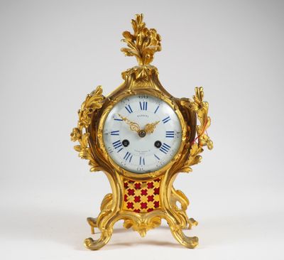 une horloge dorée ornée de motifs rouges et blancs