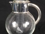 a glass pitcher with a bird on it on a black background