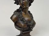 un buste en bronze représentant une femme en robe, posé sur un socle