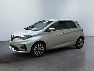 La voiture argentée est garée dans une pièce blanche au sol noir.