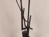 a tall black sculpture with sticks sticking out of it
