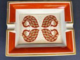 an orange and white ashtray with a dragon design on it