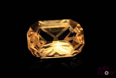 a close up of a yellow sapphire stone on a black surface