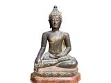 statue of a seated buddha sitting on a stone base