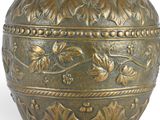 a gold vase that is sitting on a white surface