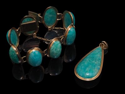 un gros plan d'un bracelet et d'une paire de boucles d'oreilles posés sur une surface noire