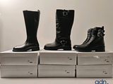 three pairs of black boots are sitting on top of boxes